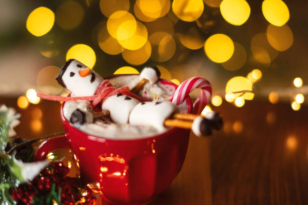istock Hot chocolate mug with marshmallow snowman and candy cane over Christmas tree background 2185866228