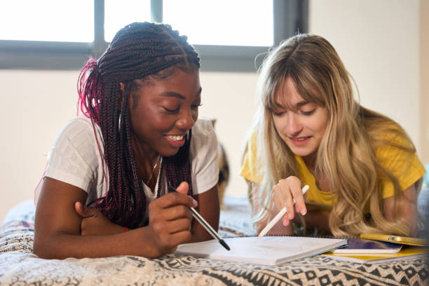 istock Two female students studying together on a bed, sharing ideas and learning 2185868645