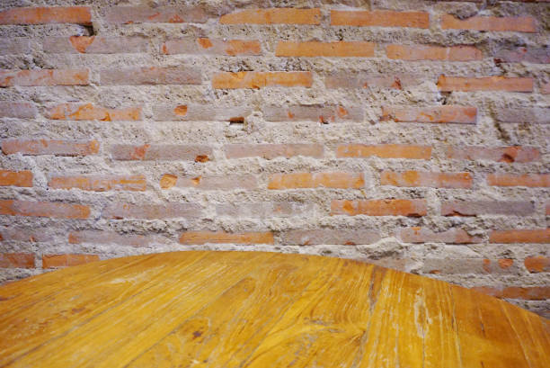 Round wooden table at front of brick wall