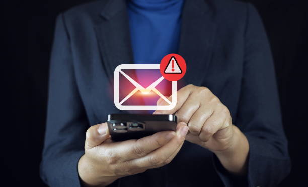 istock SMS spam, fake text message phishing from scammer concept. System hacked red warning alert, email hack, scam malware spreading virus on message alert virtual on mobile phone screen in person hand. 2185875947