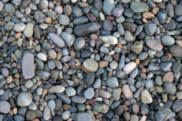 A close-up, high-angle view of a dense collection of small, multi-coloured pebbles and stones, on the banks of the River Thames in London. he mix includes natural stones, as well as fragments worn down bricks.