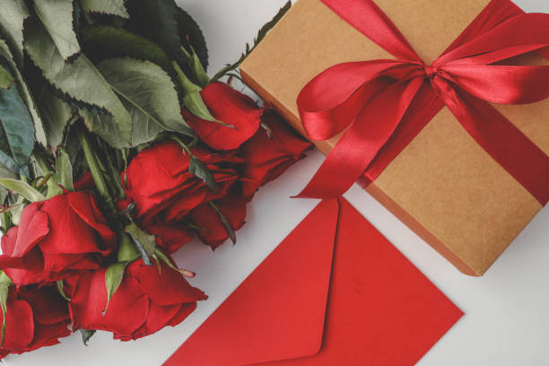 istock A bouquet of red roses, a red envelope, and a gift box adorned with a satin ribbon create a festive and romantic flat lay composition, perfect for Valentine's Day, anniversaries, or special occasions 2185877233