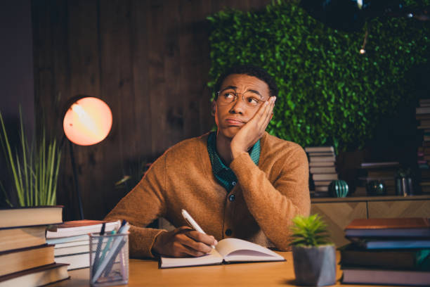 istock Young Afro-American student pondering at desk in cozy study space with books, expressing thoughtfulness and contemplation. 2185877998