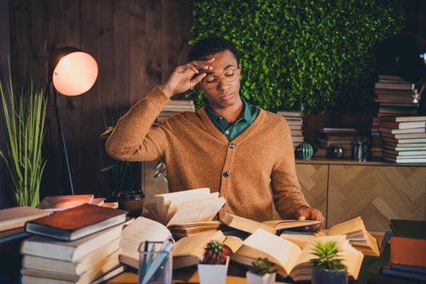 istock Young student focused on studies surrounded by books in cozy living space 2185878136
