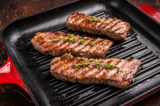 istock Grilled Tri tip steaks, marbled beef meat on pan with herbs. brown background. top view 2185879495