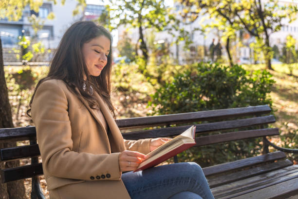 istock Young businesswoman taking a break from work sitting in the park relaxing while reading a book. Business female office worker read outdoor during lunch break to clear her mind for new job opportunity 2185879538
