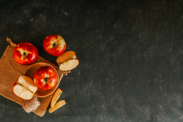 istock Fresh red apples and apple slices arranged on a rustic burlap cloth with a dark textured background, creating a cozy, autumnal food composition 2185879664