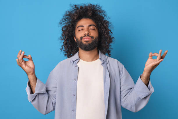 istock Calm and Serene Man Meditating With a Bright Blue Background 2185880165
