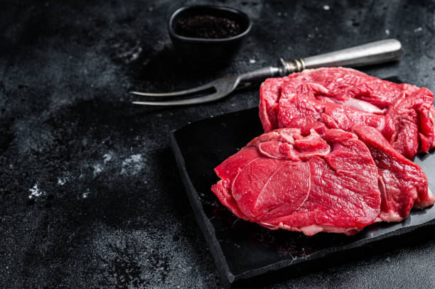 istock Raw Mutton fillet steaks from leg, uncooked lamb meat. Black background. Top view. Copy space 2185880941