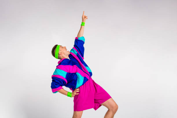 A young man in vibrant retro sportswear energetically poses against a minimalistic white backdrop, channeling a lively and humorous vibe. Perfect for themes of fitness, fashion, and fun.