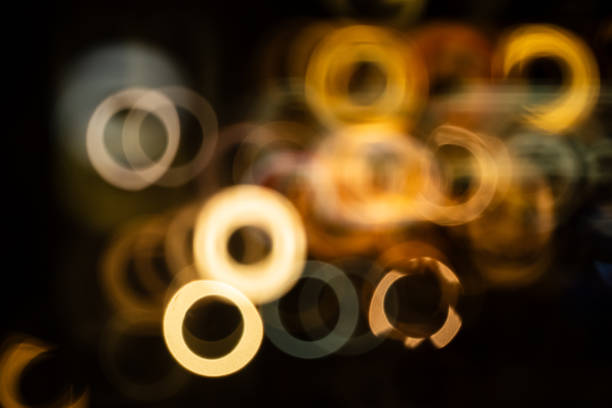 Abstract, defocused, blurry, catadioptric or reflex lens donut shaped bokeh highlights at night.