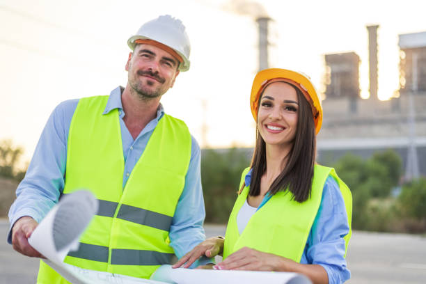 istock Two engineers reviewing blueprints on building site with power plant in background 2185885363