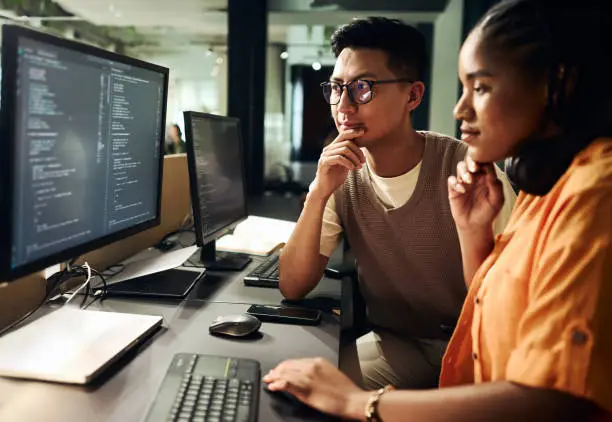 Photo of Computer programmers working on code at night in office: teamwork and problem solving