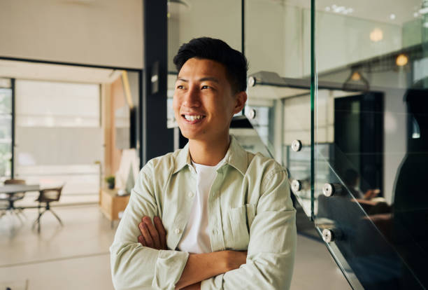 istock Smiling asian computer programmer standing with crossed arms in modern office 2185885981