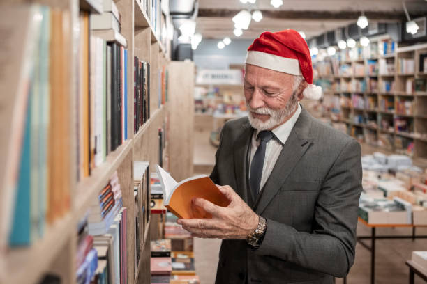 istock Elderly Man in Santa Hat Exploring Holiday Books 2185887562