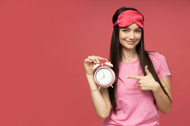 istock A young woman in a sleeping mask is holding an alarm clock 2185888569