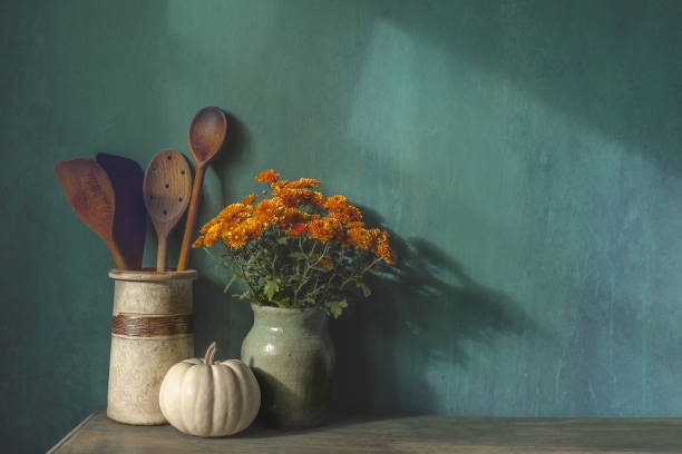 Autumn Thanksgiving background. Mockup with pumpkin, Kitchen wooden utencil and flowers on the table. Wooden table over old distressed wall with copy-space