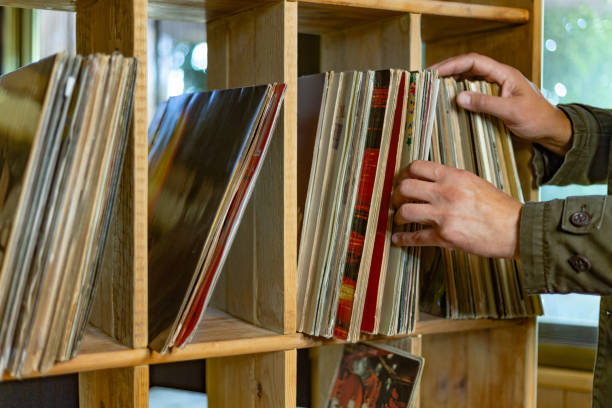 istock Hands selecting vinyl records from a wooden cubby in a retro store 2185889002