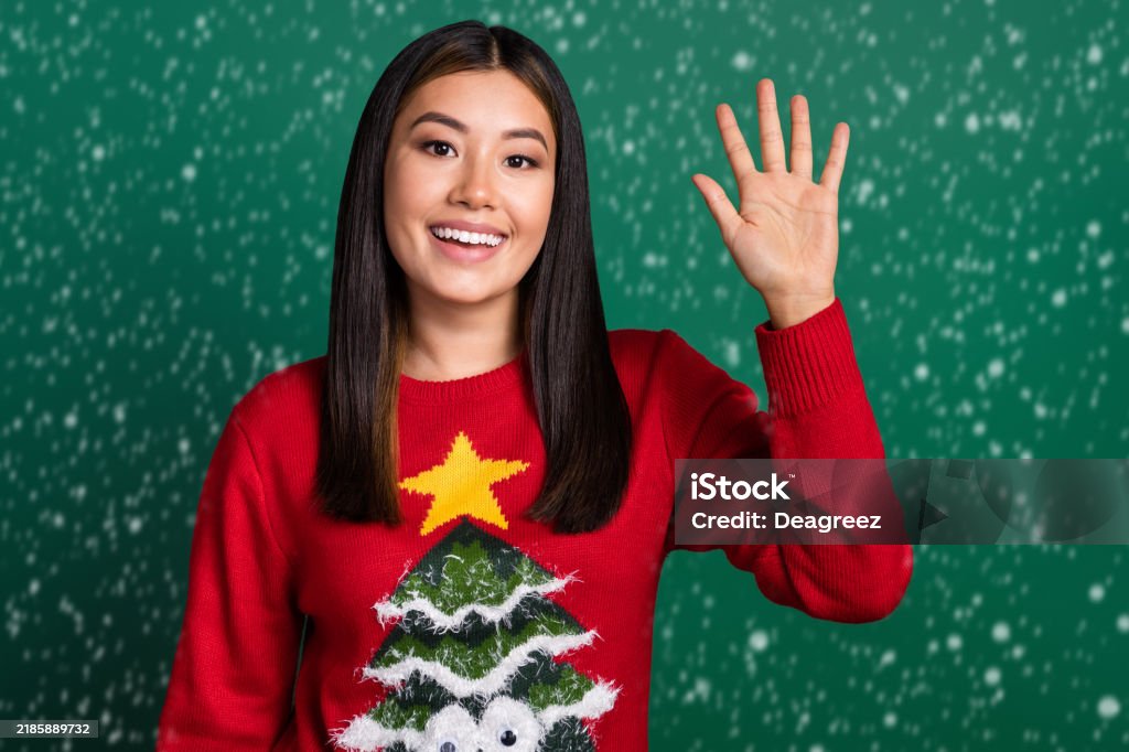 Portrait photo of young korean woman wearing red ugly sweater tree ornament raise palm five fingers up hello sign isolated on green color background - Foto de stock de 20-24 años libre de derechos Portrait photo of young korean woman wearing red ugly sweater tree ornament raise palm five fingers up hello sign isolated on green color background - Foto de stock de 20-24 años libre de derechos