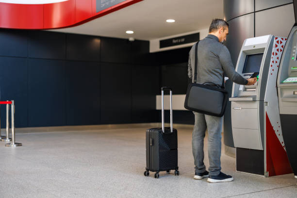 istock Man accessing ATM machine at modern transport terminal area 2185891269
