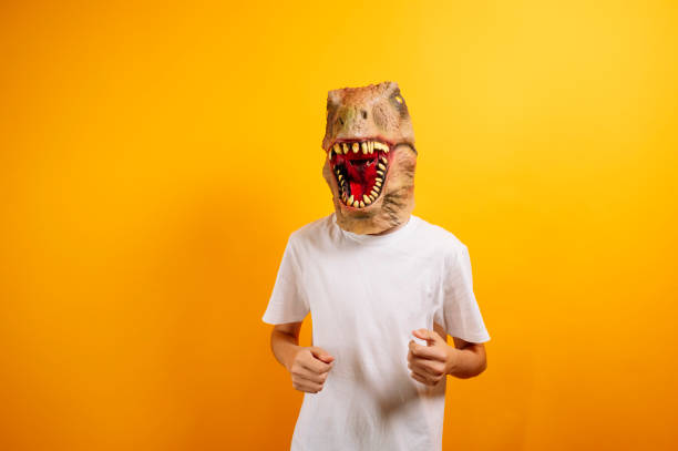 istock Teenager with T-Rex mask on yellow background 2185893169