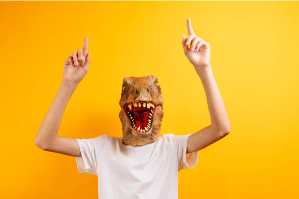 istock Teenager with T-Rex mask on yellow background 2185893200
