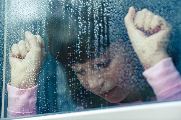 istock Sad child looking out the window on a rainy day 2185893808