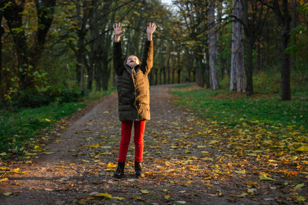 Full length of happy little girl whit raised hands having fun in autumn forest