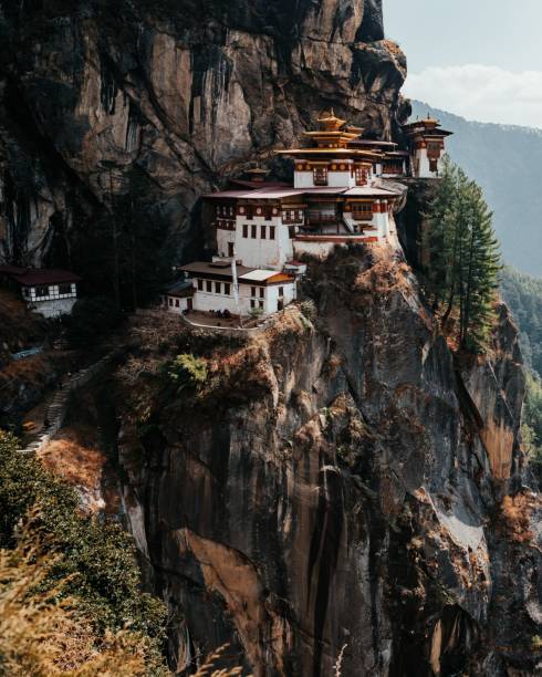 The iconic Tiger's Nest Monastery perched on a cliff in Bhutan, surrounded by lush greenery and rugged mountains.
