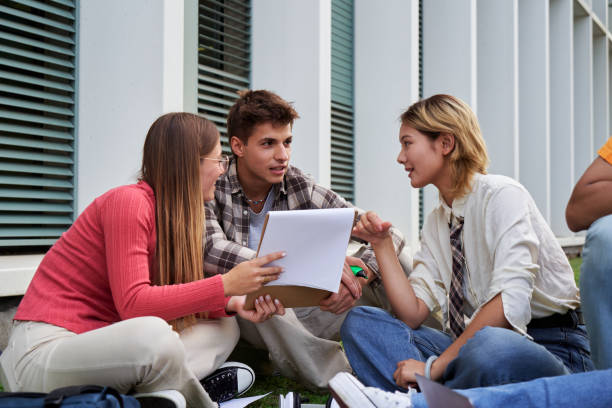 istock Three student friends sitting on the ground outside university, studying together after class. 2185900487