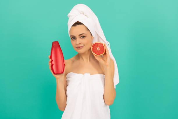 istock smiling woman with grapefruit shampoo bottle on blue background 2185901029