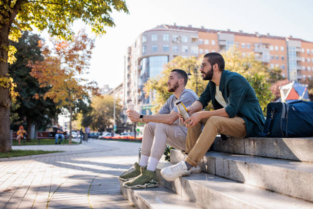 istock Male friends sitting in park 2185901574