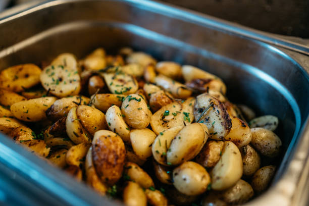 Close-up view of golden-brown roasted baby potatoes in a blue baking dish. The tender potatoes are garnished with fresh chopped herbs, showcasing a rustic and appetizing presentation. The image captures the crispy exterior and buttery finish of the perfectly cooked potatoes, making it an ideal representation of homestyle cooking and comfort food.