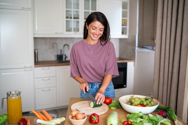istock A woman cuts a cucumber while making a salad for dinner 2185905244