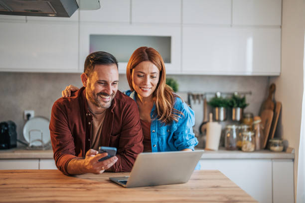 A cheerful husband and wife are standing in the kitchen.