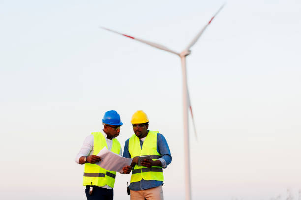 istock Two young Engineers wearing uniform ,helmet hold document inspection work in wind turbine farms rotation to generate electricity energy 2185906468