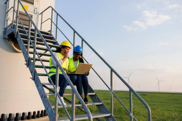 istock Two Female Engineer wearing uniform ,helmet hold document inspection work in wind turbine farms rotation to generate electricity energy 2185906541