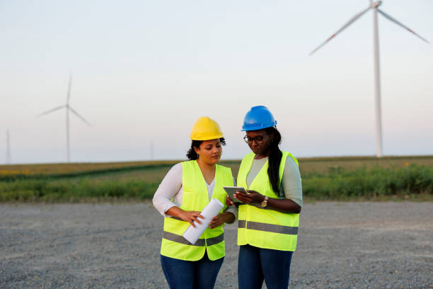 istock Two Female Engineer wearing uniform ,helmet hold document inspection work in wind turbine farms rotation to generate electricity energy 2185906590