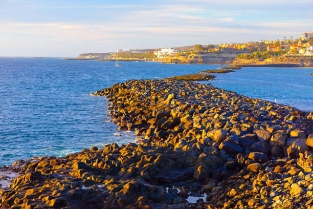 Las Americas at Costa Adeje on Tenerife in Canary Islands. Serene view of a large body of water surrounded by rocks, featuring a small boat gently floating on the surface