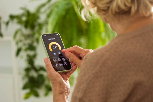 istock Senior woman using mobile phone to control termostat at home 2185907213