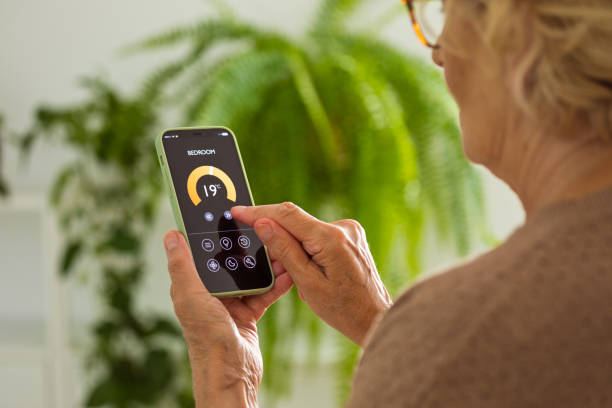Senior woman using mobile phone to control termostat at home