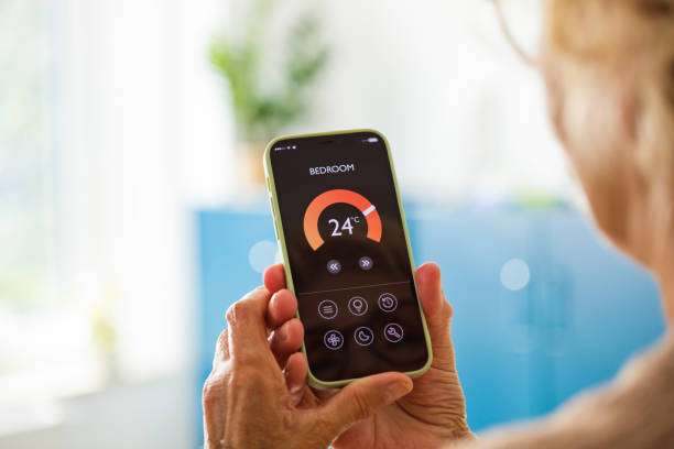 istock Senior woman using mobile phone to control termostat at home 2185907246