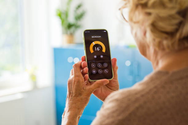 istock Senior woman using mobile phone to control termostat at home 2185907257