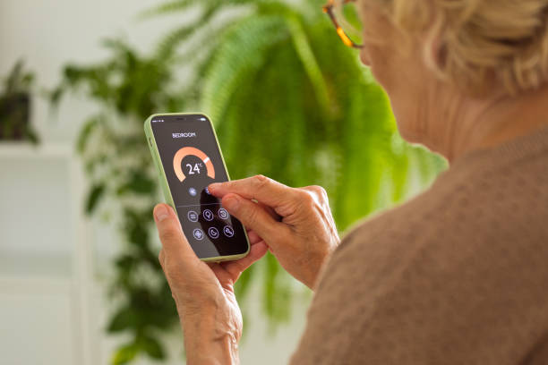 istock Senior woman using mobile phone to control termostat at home 2185907740