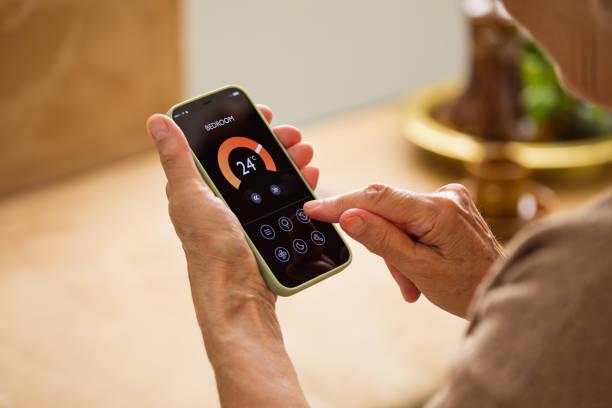 istock Senior woman using mobile phone to control termostat at home 2185907786
