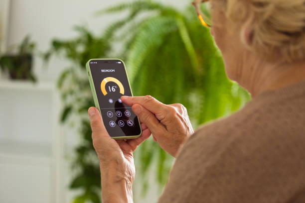 istock Senior woman using mobile phone to control termostat at home 2185907820