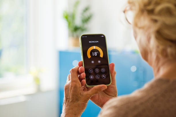 istock Senior woman using mobile phone to control termostat at home 2185907874