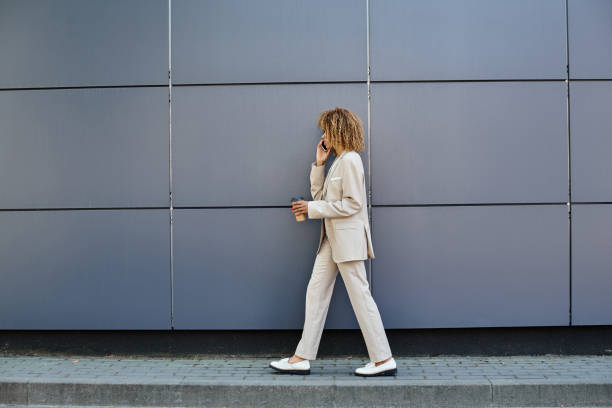 istock Young businesswoman walking confidently while talking on her phone in modern urban setting 2185908323