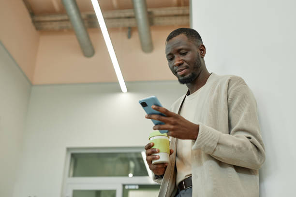 istock Black Man Text Messaging on Smartphone during Coffee Break in Office Room 2185912417