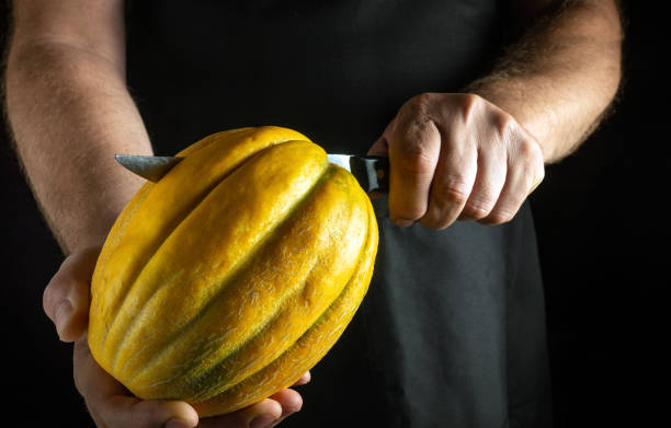 istock A skilled individual carefully carves a bright yellow melon, showcasing precise technique and artistry. The backdrop enhances the focus on the intricate details of the fruit held firmly 2185919474